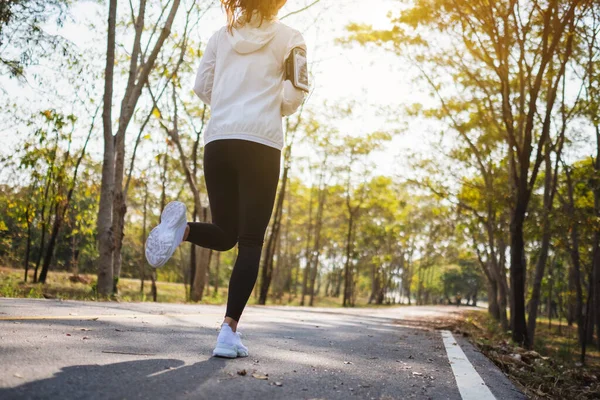 Sabahları şehir parkında koşan Asyalı bir kadının arka plan görüntüsü.