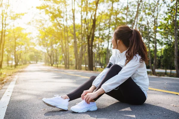 Yakından bakınca bir kadın koşucunun ayakkabı bağcıklarını bağlayıp şehir parkında koşuya hazırlandığını görüyoruz.