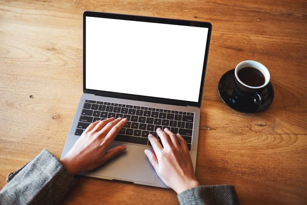 Kafedeki boş beyaz masaüstü ekran ile dizüstü bilgisayarı kullanan ve yazan bir kadının görüntüsü