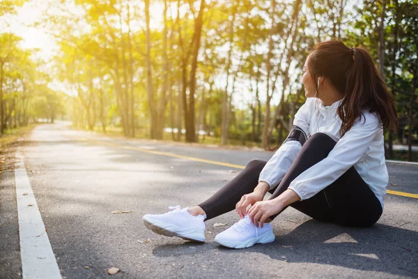 Yakından bakınca bir kadın koşucunun ayakkabı bağcıklarını bağlayıp şehir parkında koşuya hazırlandığını görüyoruz.