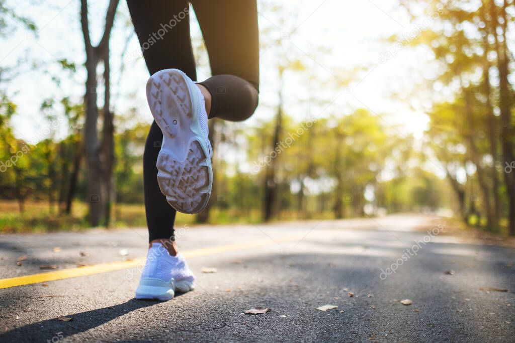 Closeup image of a woman's legs while jogging in city park in the morning