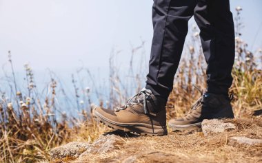 Dağların tepesinde yürüyüş yapan bir kadının yakın plan görüntüsü.