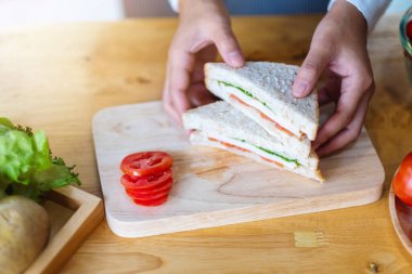 Mutfakta bir parça buğday sandviçi pişiren ve elinde tutan bir kadın şefin yakın plan fotoğrafı.