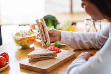 Mutfakta buğday ekmeği pişirip yiyen bir kadın şefin yakın plan görüntüsü.