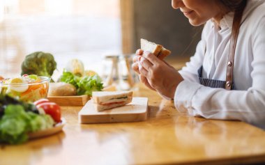 Mutfakta buğday ekmeği pişirip yiyen bir kadın şefin yakın plan görüntüsü.
