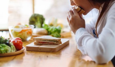 Mutfakta buğday ekmeği pişirip yiyen bir kadın şefin yakın plan görüntüsü.