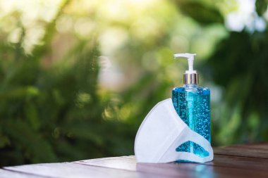 Covid-19 önleme konsepti için koruyucu bir yüz maskesi ve bir şişe el dezenfektanı alkolü jeli.