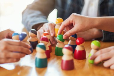 İnsanlar masadaki bir gruptan tahta figürleri seçip alıyor.