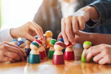 İnsanlar masadaki bir gruptan tahta figürleri seçip alıyor.
