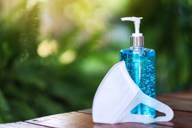 Covid-19 veya 2020 virüs önleme konsepti için koruyucu bir yüz maskesi ve bir şişe el dezenfektanı alkolü jeli.