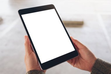 Sokakta elinde siyah tablet olan beyaz ekranlı bir kadının görüntüsü.