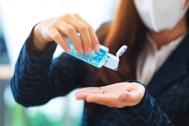 Koruyucu maske takan ve sağlık hizmetleri ve Covid-19 veya 2020 virüs konsepti için temiz ellere alkol jeli süren bir kadının yakın plan görüntüsü