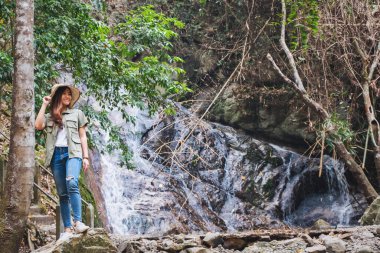 Ormanda şelalenin önünde duran güzel bir Asyalı kadın.