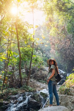 Ormanda şelalenin önünde duran güzel bir Asyalı kadın.