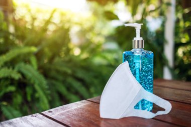 Covid-19 veya 2020 virüs önleme konsepti için koruyucu bir yüz maskesi ve bir şişe el dezenfektanı alkolü jeli.