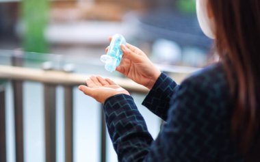 Sağlık ve Covid-19 veya 2020 virüs konsepti için koruyucu yüz maskesi takan ve temiz ellere alkol jeli süren bir kadının yakın plan görüntüsü