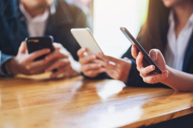 Birlikte otururken cep telefonunu kullanan ve ona bakan bir grup insan.
