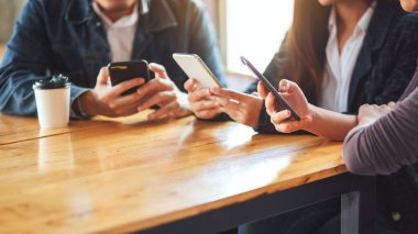 Birlikte otururken cep telefonunu kullanan ve ona bakan bir grup insan.