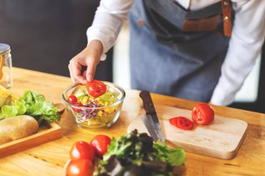 Mutfakta taze karışık sebze salatası pişiren kadın aşçının yakın plan görüntüsü.