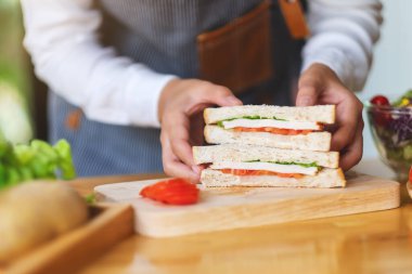 Mutfakta bir parça buğday sandviçi pişiren ve elinde tutan bir kadın şefin yakın plan fotoğrafı.