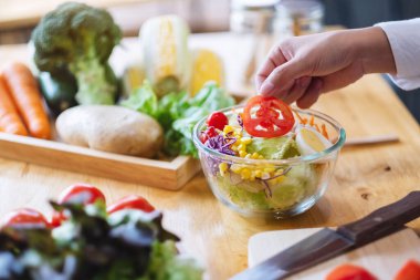 Mutfakta taze karışık sebze salatası pişiren kadın aşçının yakın plan görüntüsü.