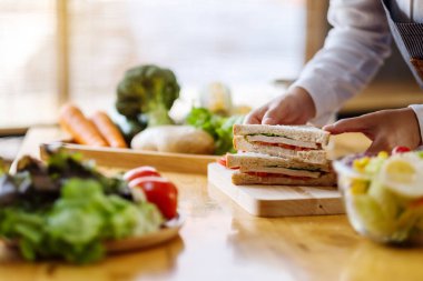 Mutfakta bir parça buğday sandviçi pişiren ve elinde tutan bir kadın şefin yakın plan fotoğrafı.