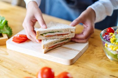 Mutfakta bir parça buğday sandviçi pişiren ve elinde tutan bir kadın şefin yakın plan fotoğrafı.