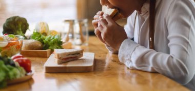 Mutfakta buğday ekmeği pişirip yiyen bir kadın şefin yakın plan görüntüsü.
