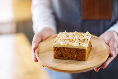 Bir garson, ev yapımı havuçlu keki ahşap tepside servis ediyor.