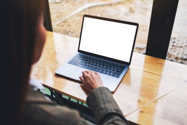 Mockup image of a businesswoman using and typing on laptop computer with blank white desktop screen on wooden table