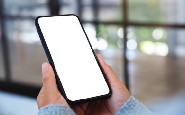 Boş beyaz masaüstü ekranlı cep telefonu tutan bir kadının görüntüsü 