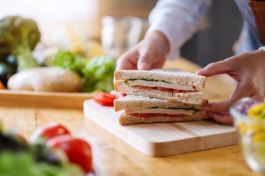 Mutfakta bir parça buğday sandviçi pişiren ve elinde tutan bir kadın şefin yakın plan fotoğrafı.