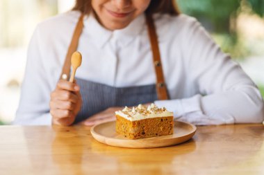 Güzel bir kadın şef ahşap tepside ev yapımı havuçlu kek pişiriyor ve yiyor.