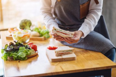 Mutfakta bir parça buğday sandviçi pişiren ve elinde tutan bir kadın şefin yakın plan fotoğrafı.