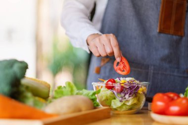 Mutfakta taze karışık sebze salatası pişiren kadın aşçının yakın plan görüntüsü.