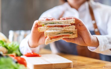 Kadın bir aşçının yemek pişirirken ve mutfakta buğdaylı sandviç gösterirken yakın plan görüntüsü.