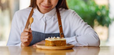 A beautiful female chef baking and eating a piece of homemade carrot cake in wooden tray