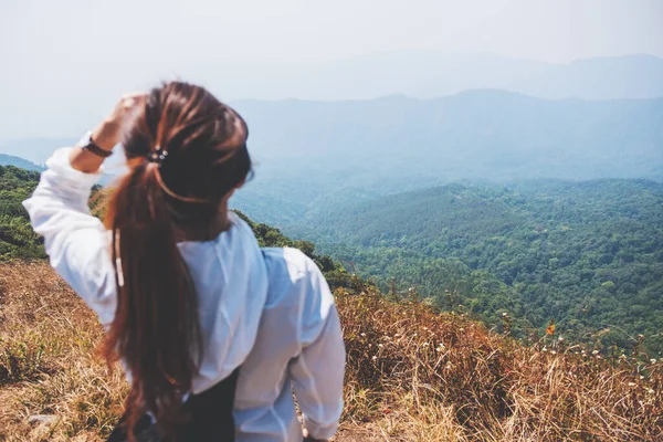 Dağların tepesinde yürüyüş yapan ve güzel manzaraya bakan bir kadın.