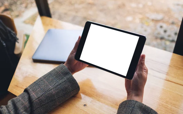 Siyah tabletli, beyaz ekranlı ve tahta masadaki laptoplu bir kadının görüntüsü. 