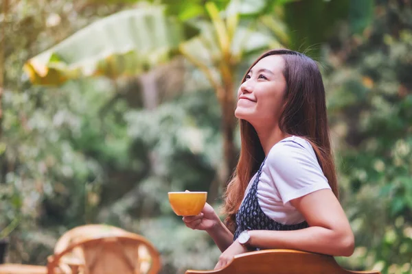 Açık havada elinde sıcak kahve tutan ve içen Asyalı güzel bir kadının yakın çekimi.