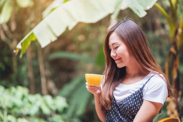 Açık havada elinde sıcak kahve tutan ve içen Asyalı güzel bir kadının yakın çekimi.
