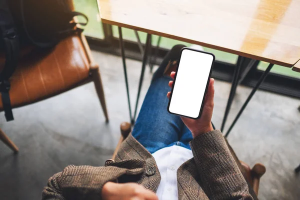 Ofiste otururken elinde boş beyaz ekranla cep telefonu tutan bir kadının üst görünüm görüntüsü