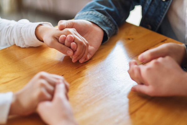 Group of people sitting in a circle holding hands and pray together or in therapy session 