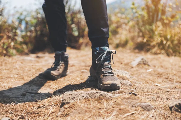 Closeup image of a woman hiking with trekking boots on the top of mountain