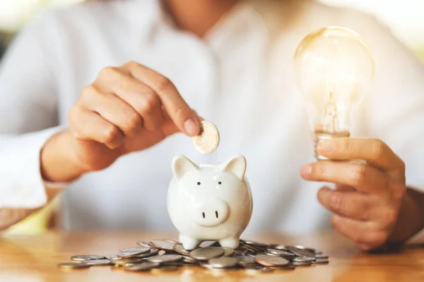 Uma Mulher Segurando Lâmpada Colocar Moedas Banco Porquinho Para Economizar — Fotografia de Stock