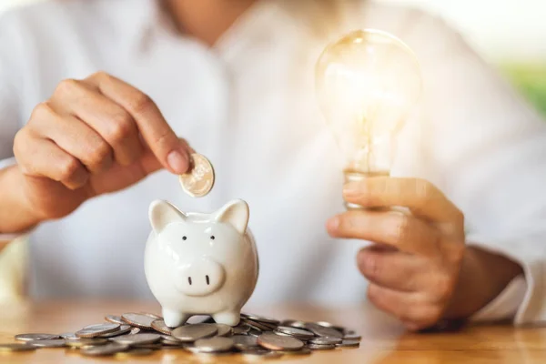 Uma Mulher Segurando Lâmpada Colocar Moedas Banco Porquinho Para Economizar — Fotografia de Stock