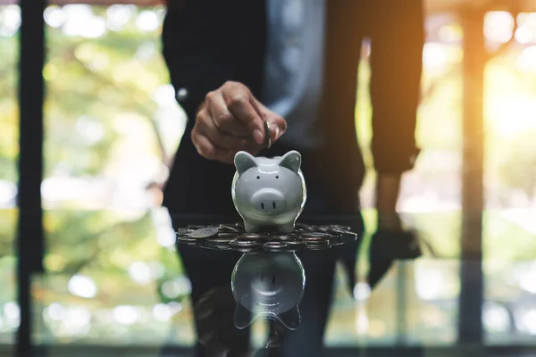 Uma Mulher Colocando Moedas Banco Porquinho Pilha Moedas Mesa Para — Fotografia de Stock