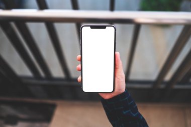 Üst görünüm, elinde cep telefonu olan bir kadının kapalı alanda beyaz ekran görüntüsü.