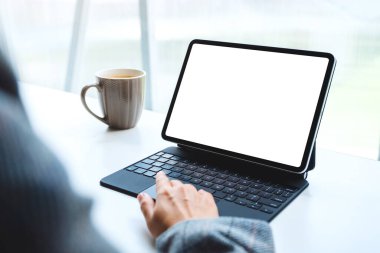Tablet dokunmatik bilgisayarında bilgisayar bilgisayarı olarak beyaz ekran kullanan ve dokunan bir kadının görüntüsü, masada kahve fincanı.