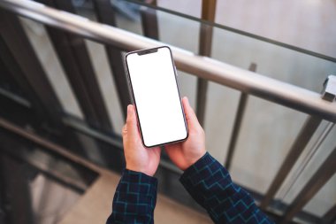 Üst görünüm, elinde cep telefonu olan bir kadının kapalı alanda beyaz ekran görüntüsü.